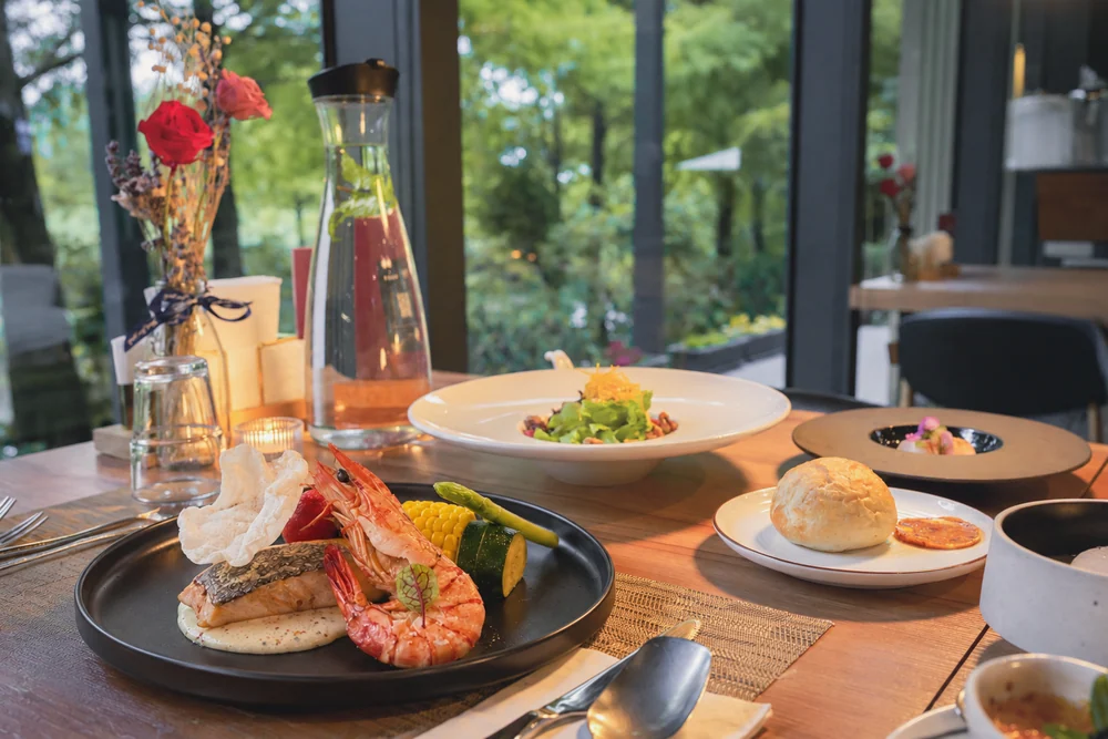Seafood main, bread and set-menu courses on a window table at Loherb Cuisine