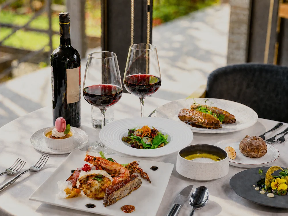 Main course, salad, soup, dessert and red wine on a Loherb Cuisine table